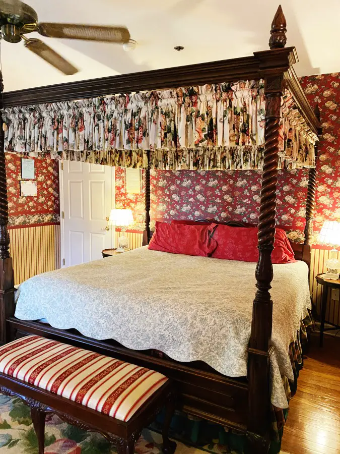 four poster bed with red rose wallpaper at Heron Cay in Mount Dora